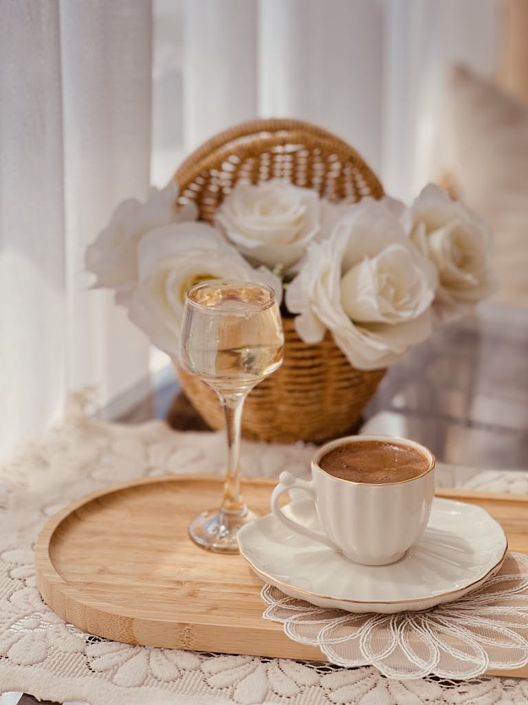 A serene coffee setting indoors with white roses and wine, bathed in natural light, perfect for a relaxed lifestyle vibe.